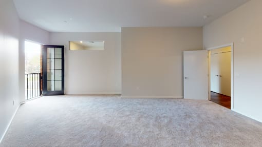 an empty living room with a door to a balcony