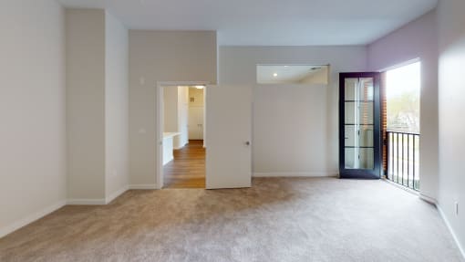 a living room with a door to a hallway and a carpeted floor