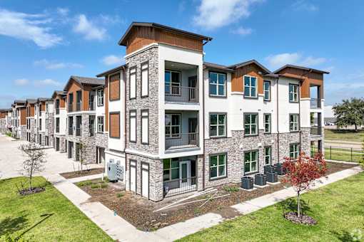 an exterior view of a row of apartment buildings on a sunny day at Creekside at Grand Prairie, Grand Prairie, Texas, 75052