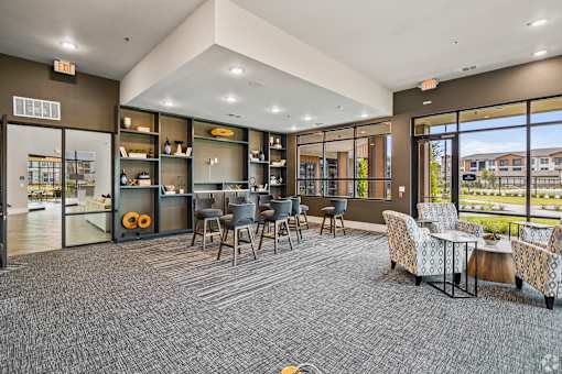 a lounge area with chairs and tables and large windows at Creekside at Grand Prairie, Grand Prairie, Texas