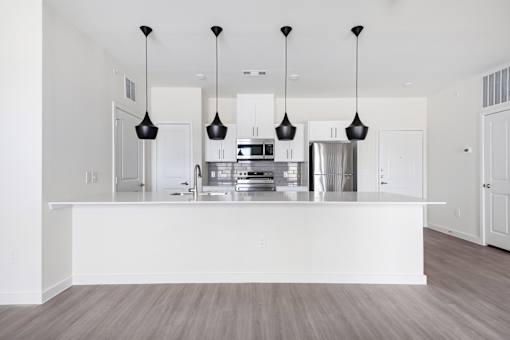 A modern kitchen with a white island and pendant lights.