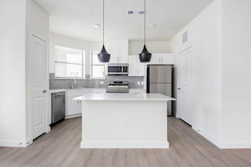 A modern kitchen with a white island and pendant lights.