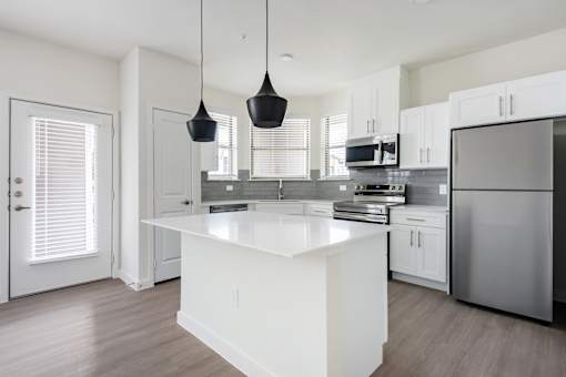 A modern kitchen with a white island and stainless steel appliances.