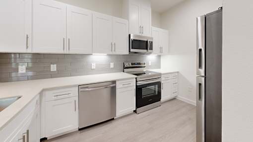 A modern kitchen with white cabinets and stainless steel appliances.