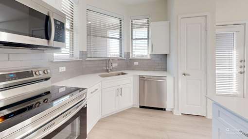 A modern kitchen with stainless steel appliances and white cabinetry.
