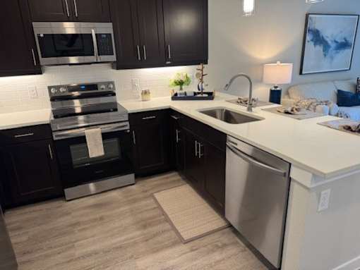 A modern kitchen with dark brown cabinets and stainless steel appliances at Arden at Corinth, Corinth, Texas