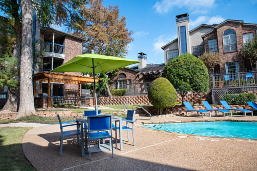 our apartments have a pool and patio with chairs and umbrella at Infinity on the Mark, Dallas, TX, 75243