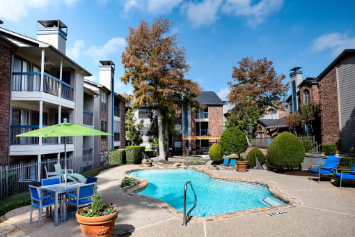 our apartments have a large pool and patio with chairs and umbrellas at Infinity on the Mark, Dallas, Texas
