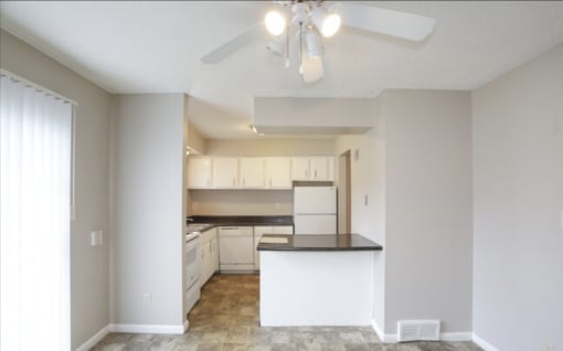 an empty kitchen with white cabinets and a ceiling fan