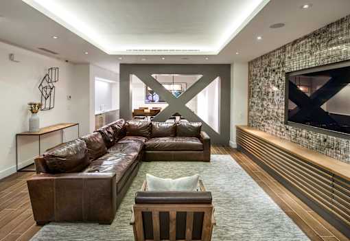 A modern living room with a brown leather couch and a large TV mounted on the wall.