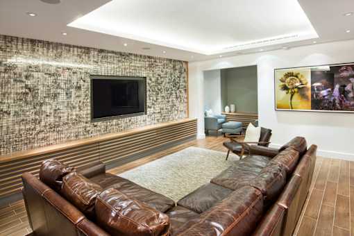 A living room with a stone wall and a brown leather couch.