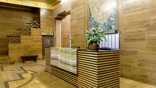 A reception desk with a plant on top and a painting on the wall.