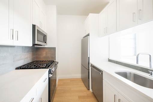A kitchen with white cabinets and a stove top oven.