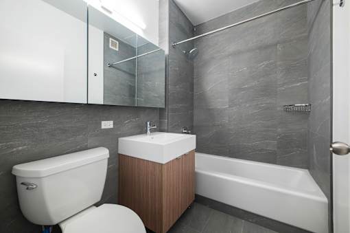 A modern bathroom with a white toilet, sink, and bathtub.