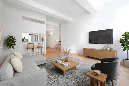 A modern living room with a grey couch, a wooden coffee table, and a black armchair.