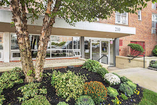 A building with the number 210 on it has a landscaped garden in front.