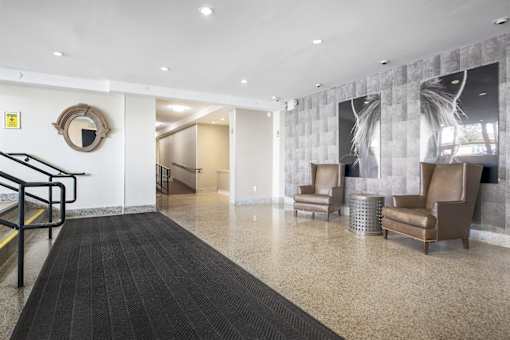 A hallway with a black carpet and a mirror on the wall.
