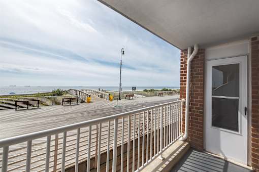 A balcony with a white railing and a view of the beach.