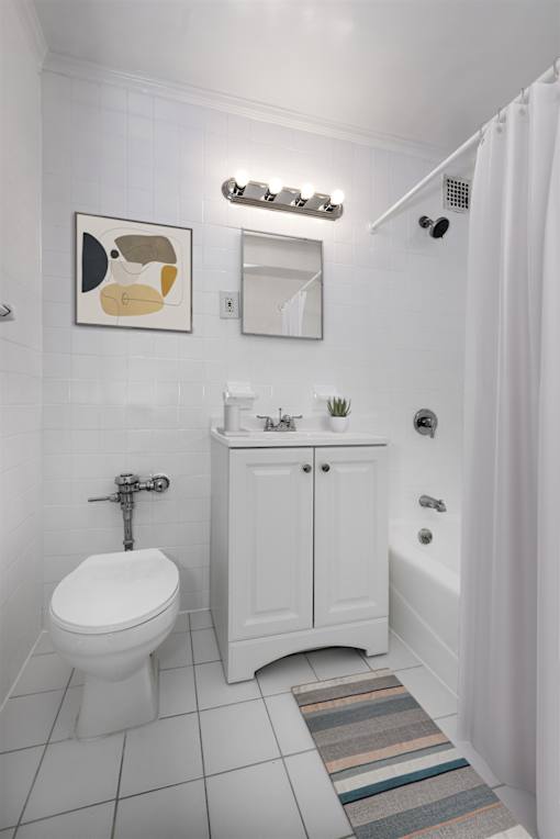 A white bathroom with a toilet, sink, and shower.