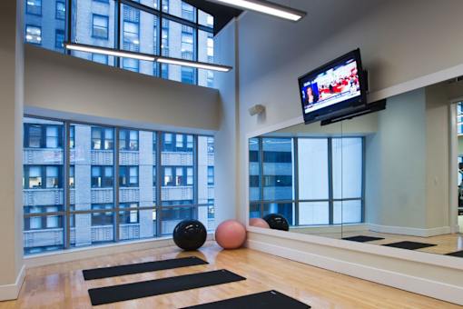 A room with a yoga mat, a ball and a television.at 'The Metropolis', New York 