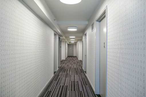 A long hallway with a carpeted floor and white walls.at 'The Metropolis', New York 