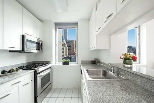 A modern kitchen with white cabinets and a view of the city.at 'The Metropolis', New York 