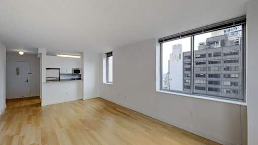 A room with wooden floors and a large window overlooking a cityscape.at 'The Metropolis', New York, 10017 