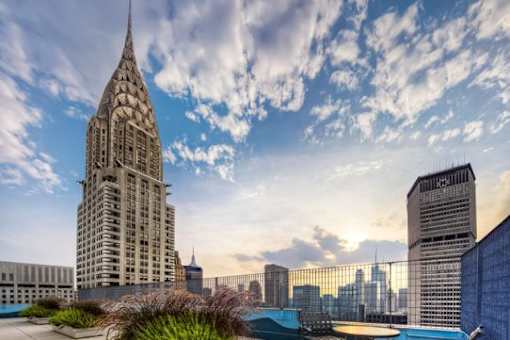A tall building with a pointed spire stands out against a city skyline.at 'The Metropolis', New York, NY 10017 