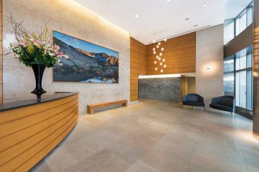 A reception area with a wooden counter and a large painting of a mountain scene.at 'The Metropolis', New York, 10017 