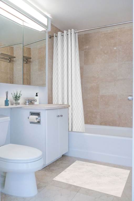 A white toilet sits in a bathroom with a white shower curtain.at 'The Metropolis', New York, 10017 