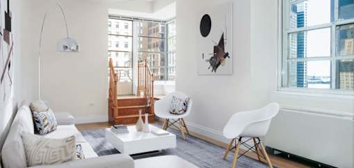 A white chair sits in a room with a white couch and a white coffee table.at 21 West, New York, 10006
