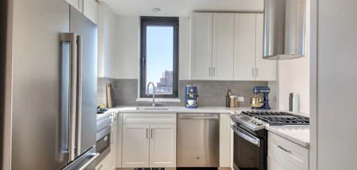 A modern kitchen with white cabinets and stainless steel appliances.at 301E94, New York, NY 