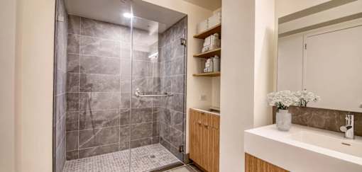 A modern bathroom with a walk-in shower and a white sink.at 301E94, New York New York 