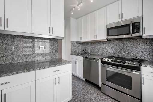 A kitchen with granite countertops and stainless steel appliances at The Caldwell Apartments, New York, NY, 10028