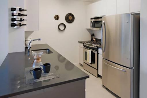 A kitchen with a stainless steel refrigerator and oven at The Maximilian Apartments, New York, 11101