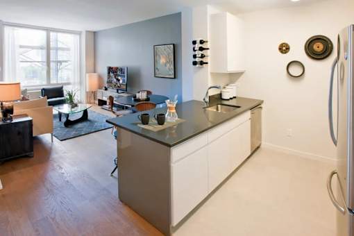 A modern kitchen with a refrigerator on the right side at The Maximilian Apartments, Long Island City