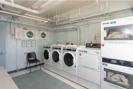 A laundry room with a row of washers and dryers.