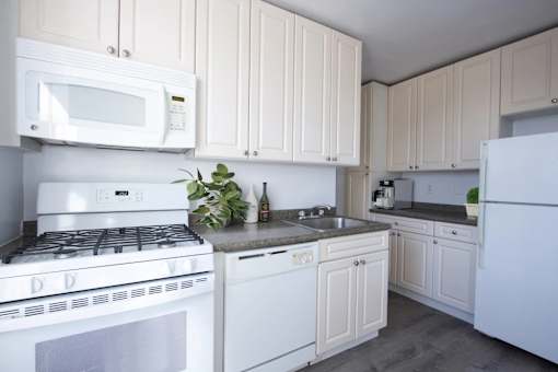 A white kitchen with a stove, microwave, and refrigerator.