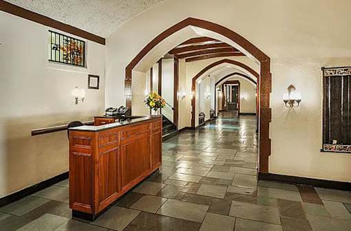 A hallway with a wooden reception desk and a vase of flowers on top. at Sutton Collection Apartments, New York