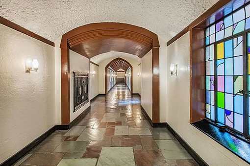 A long hallway with a stained glass window on the right. at Sutton Collection Apartments, New York, New York