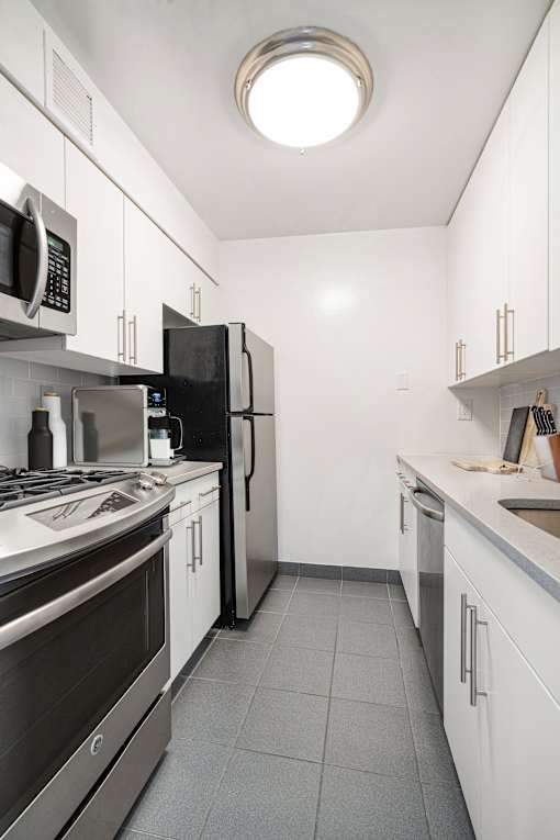 A modern kitchen with stainless steel appliances and white cabinets. at The Ellington Apartments, New York