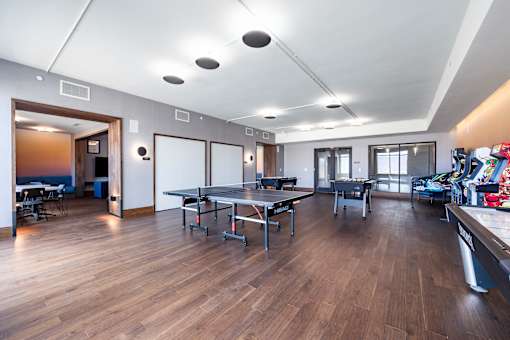 a large room with a ping pong table and a dining room with chairs and