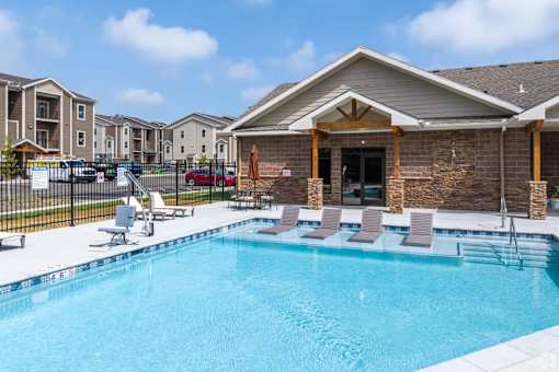 A swimming pool with lounge chairs and a building in the background.