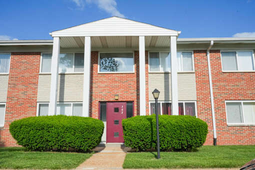 A red door is on the front of a brick building.