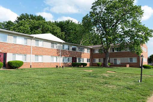 A large grassy area in front of a building with a tree.