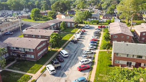 A parking lot with cars and apartment buildings in the background.