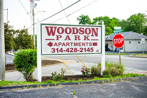 A sign for Woodson Park Apartments with a phone number on it.