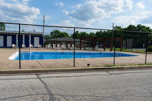 A pool surrounded by a black fence and a building in the background.