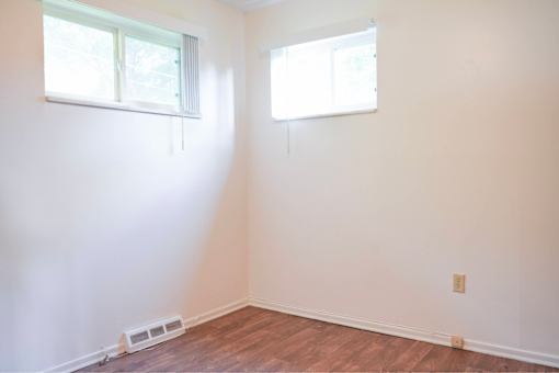 A room with a window and a wooden floor.