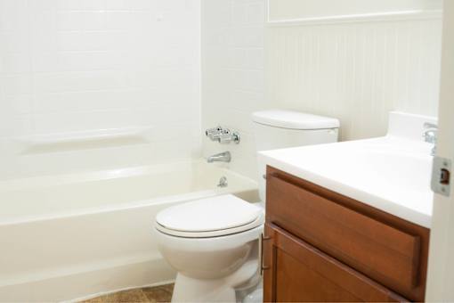 A white toilet sits next to a bathtub in a bathroom.